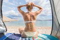 Rear view of beautiful young caucasian woman enjoying summer sun on Mediterranean beach protected from heat and sunburns Royalty Free Stock Photo