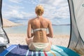 Rear view of beautiful young caucasian woman enjoying summer sun on Mediterranean beach protected from heat and sunburns Royalty Free Stock Photo