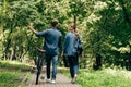 rear view of beautiful young couple in denim shirts with bicycle walking