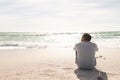 Rear view of biracial senior man looking at horizon over sea from beach shore during sunny day Royalty Free Stock Photo