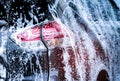 Rear view of black compact SUV car with sport and modern design are washing with water and white foam. Car care service business. Royalty Free Stock Photo