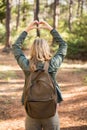Rear view of blonde hiker framing heart with hands