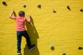 Rear view of boy climbing on yellow wall Royalty Free Stock Photo