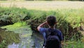 Rear View of Boy Holding Camera and Gimble While Filming a Country Stream on a Summers Day