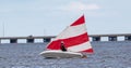 Rear view of a boy sailing a sunfish sailboat in the bay with a strong wind