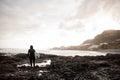 Rear view brunette boy standing in the black swimsuit with a white surf in his hands on the shore Royalty Free Stock Photo