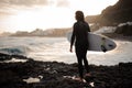 Rear view brunette boy standing with a surf in his hands on the shore on the sunset Royalty Free Stock Photo