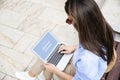 Rear view of a brunette haired woman sitting outdside and using laptop