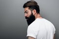 Rear view of brutal attractive young bearded male model looking aside, posing on a gray studio background. Portrait of handsome