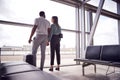 Rear View Of Business Couple With Luggage Standing By Window In Airport Departure Lounge Royalty Free Stock Photo