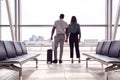 Rear View Of Business Couple With Luggage Standing By Window In Airport Departure Lounge Royalty Free Stock Photo