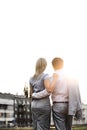 Rear view of business couple standing with arms around against clear sky on sunny day Royalty Free Stock Photo