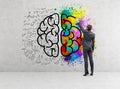 Rear view of businessman drawing colorful brain icon on concrete Royalty Free Stock Photo