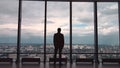 Rear view of businessman in an office with panoramic city view. Businessman admires the city from the panoramic Windows Royalty Free Stock Photo