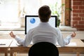 Rear view businessman sitting at desk opposite pc doing yoga