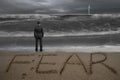 Rear view businessman standing facing fear word on sand beach