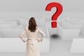 Rear view of businesswoman with hands on hips looking at question mark over maze Royalty Free Stock Photo