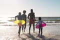 Rear view of cheerful african american parents and children running in sea against clear sky Royalty Free Stock Photo