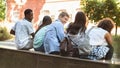 Rear view of cheerful college students relaxing outdoors after classes