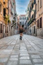 Rear view of a cheerful dancing and walking along the central streets of Venice, vertical