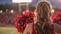 Rear view of a cheerleader with red pom-poms at a football game Royalty Free Stock Photo