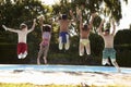 Rear View Of Children Jumping Into Outdoor Swimming Pool