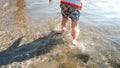 Rear view closeup photo of little boy standing in sea waves at beach Royalty Free Stock Photo