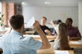 Rear view of company employee launching paper plane towards cowo