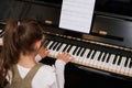 Rear view little child girl performing the rhythm of classical music while playing grand piano, putting fingers on keys Royalty Free Stock Photo