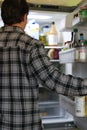 Rear View Of A Confused Young Man Looking At Food In Refrigerator Royalty Free Stock Photo