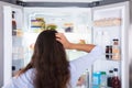 Confused Woman Looking In Open Refrigerator Royalty Free Stock Photo