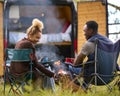 Rear View Of Couple Camping In Countryside With RV Drinking Coffee By Outdoor Fire With Pet Dog Royalty Free Stock Photo