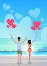 Rear view couple holding pink heart shape air balloons sea ocean beach summer vacation concept man woman in love over