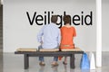 Rear view of couple reading Dutch text Veiligheid (security) and contemplating it