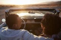 Rear View Of Couple On Road Trip Driving Classic Convertible Car Towards Sunset Royalty Free Stock Photo