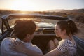 Rear View Of Couple On Road Trip Driving Classic Convertible Car Towards Sunset Royalty Free Stock Photo