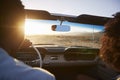 Rear View Of Couple On Road Trip Driving Classic Convertible Car Towards Sunset Royalty Free Stock Photo