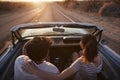 Rear View Of Couple On Road Trip Driving Classic Convertible Car Towards Sunset Royalty Free Stock Photo