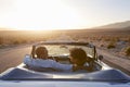 Rear View Of Couple On Road Trip Driving Classic Convertible Car Towards Sunset Royalty Free Stock Photo