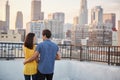 Rear View Of Couple On Rooftop Terrace Looking Out Over City Skyline At Sunset Royalty Free Stock Photo