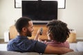 Rear View Of Couple Sitting On Sofa Watching TV Together