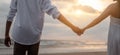 Rear view of couple standing holding hands each other while at beach at sunrise, plan life at future concept.