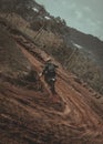 Rear view of a crazy motor cyclist (biker) in dirt riding their off-road motorbike
