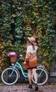 Curly woman against bicycle parked to wall covered with ivy. Royalty Free Stock Photo