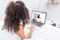 Rear view of curly woman using laptop with ebay on screen in bed