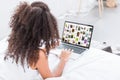 Rear view of curly woman using laptop with pinterest on screen in bed