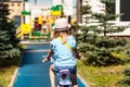 Rear view cute adorable little blond girl enjoy riding small bicycle by path in green summer park Royalty Free Stock Photo