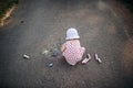 A rear view of cute toddler girl outdoors in countryside, chalk drawing on road. Royalty Free Stock Photo