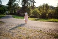 A rear view of cute toddler girl walking outdoors on road in countryside . Royalty Free Stock Photo