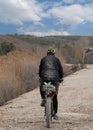 Rear view of cyclist riding on mud dirt road and completely muddy clothes Royalty Free Stock Photo